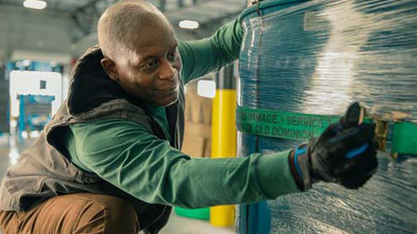 OD employee strapping barrels for secure transport in truck