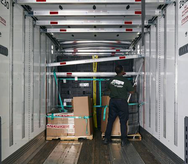 Dock Worker installing deck bars to protect and support freight in trailer. 