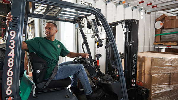 dock worker backing forklift out of trailer with freight