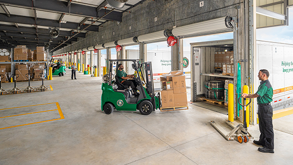 ODFL workers loading freight at a service center dock with forklifts and pallet jacks.