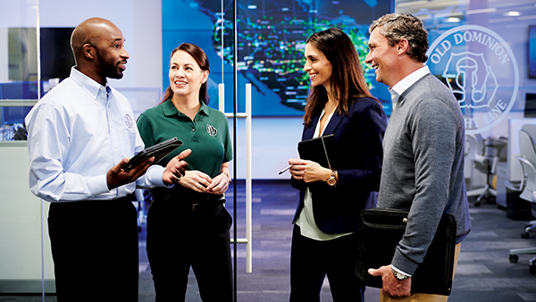 Male and Female Sales Reps Talking to Male and Female Clients in front of the command center